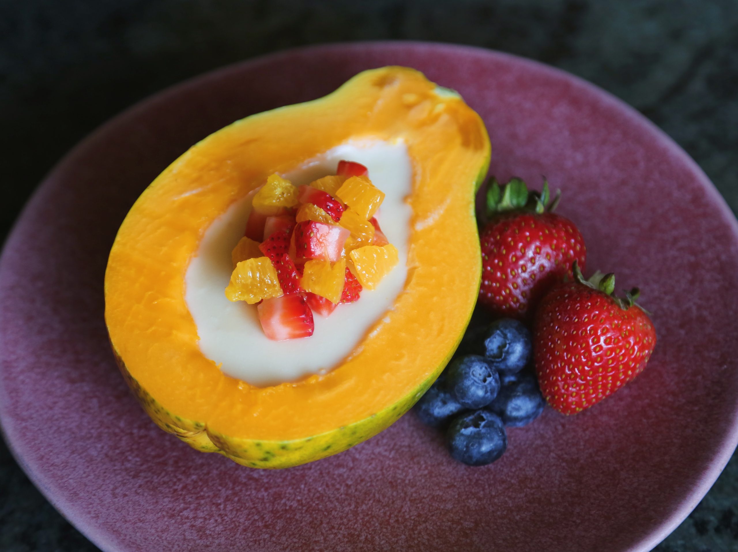orange panacotta with fresh papaya with other fruits on a plate