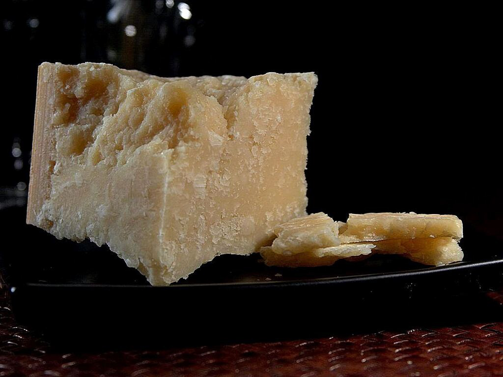 Block of parmesan cheese on black plate