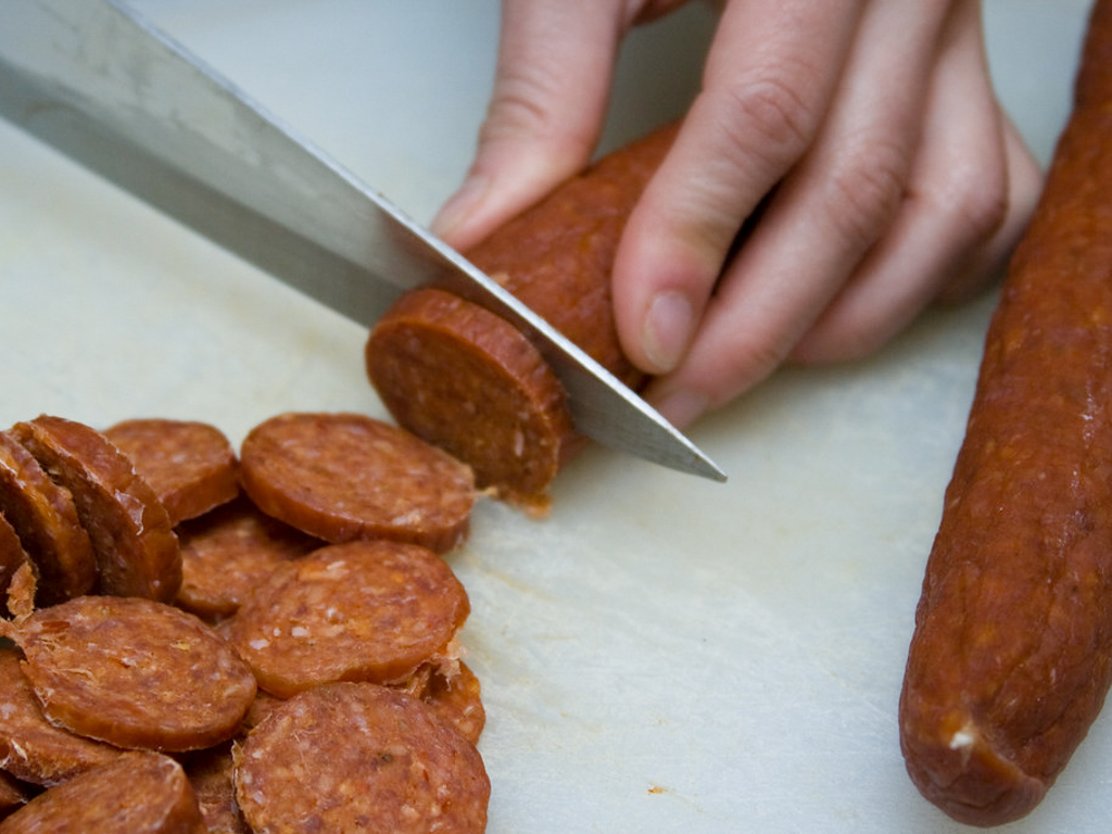 Pepperoni being sliced