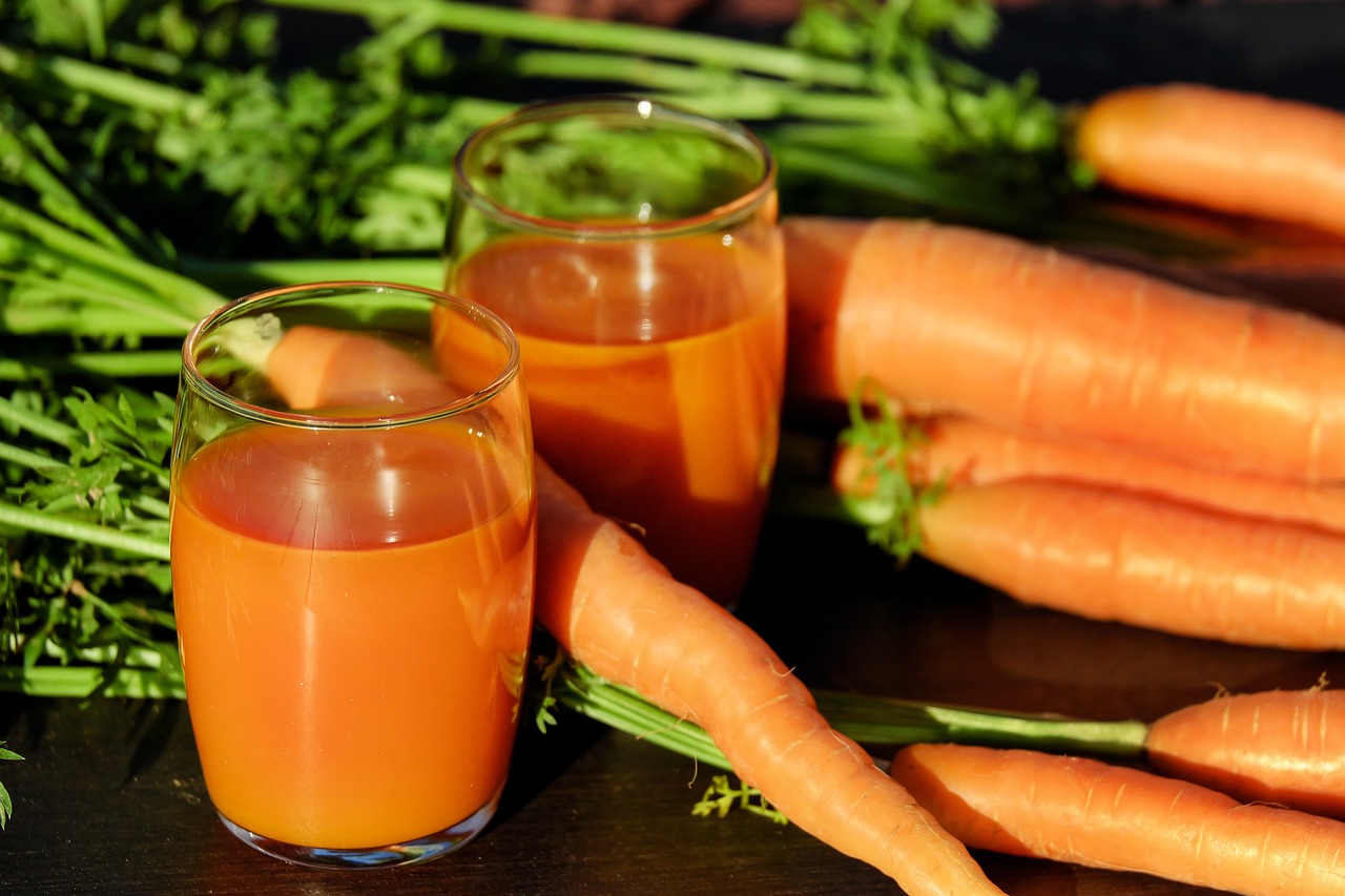 carrot juice in two glass cups with whole carrots