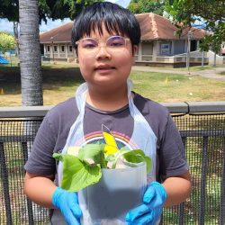 Child posing with transplanted bok choy seedling