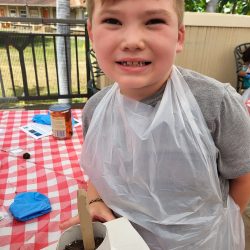 Child posing with newspaper pot with bok choy seeds planted