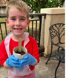 Child posing with newspaper pot with bok choy seeds planted