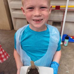 Child posing with newspaper pot with bok choy seeds planted