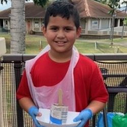 Child posing with newspaper pot with bok choy seeds planted