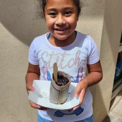 Child posing with newspaper pot with bok choy seeds planted