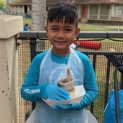 Child posing with newspaper pot with bok choy seeds planted