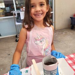 Child posing with newspaper pot with bok choy seeds planted