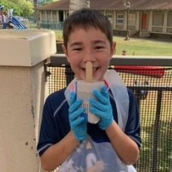 Child posing with newspaper pot with bok choy seeds planted