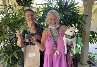 Two recipients posing with green bean seedling kits and dog